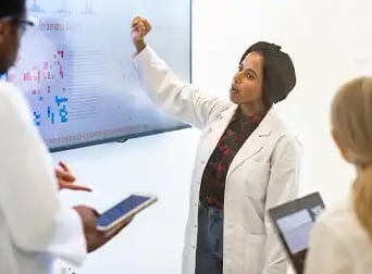 A group of healthcare professionals discussing research on a display
