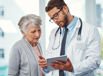 A healthcare professional showing results on a digital tablet to a patient